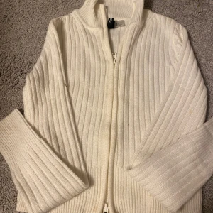 Vit ribbad kofta från H&M - Säljer en superfin vit ribbad kofta från H&M i storlek S. Den har en dragkedja framtill och långa ärmar, perfekt för kyliga dagar. Koftan är i mycket bra skick och passar både till vardags och lite finare tillfällen. Ett måste i garderoben! 🤍