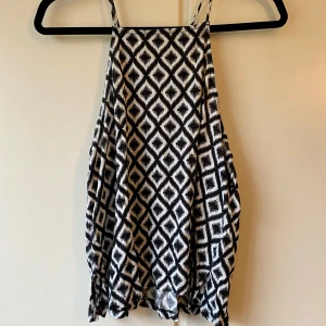 Svartvit mönstrad linnetopp - Snygg och luftig svartvit linnetopp med geometriskt mönster. Toppen har smala axelband och en lös passform som ger en bekväm känsla. 