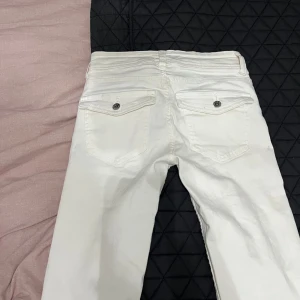 Vita bootcut jeans - Säljer ett par snygga vita bootcut jeans i mycket bra skick. De är lågmidjade med knappar och dragkedja fram. Perfekta för både vardag och fest! 🕺