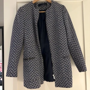 Mönstrad kappa - Säljer en mönstrad kappa från Zara i mörkblå och vit. Den har en stilren design med dragkedjedetaljer och långa ärmar. Perfekt för höst och vår! På etiketten står det att den är i storlek M men den känns mer som en XS/S.