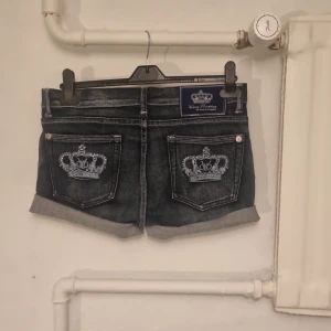 Mörkblå jeansshorts med broderade kronor - Säljer ett par snygga mörkblå jeansshorts från victoria beckham. De har broderade kronor på bakfickorna och Shortsen är uppvikta nertill. Säljer eftersom jag ibte använder dem, med de är i jätte bea skick