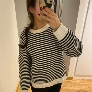 Randig stickad tröja från Lindex - Säljer en superfin randig stickad tröja från Lindex i svart och vitt. Den har en bekväm passform med långa ärmar och ribbade kanter vid hals, ärmslut och nederkant. Perfekt för höst och vinter! 🖤🤍