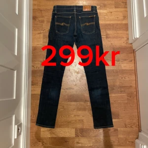 Mörkblå jeans från Nudie Jeans - Säljer ett par snygga mörkblå jeans från Nudie Jeans i storlek W28 L32. De är i mycket bra skick! Passformen är slim/skinny och de har en stilren look med orange sömmar.