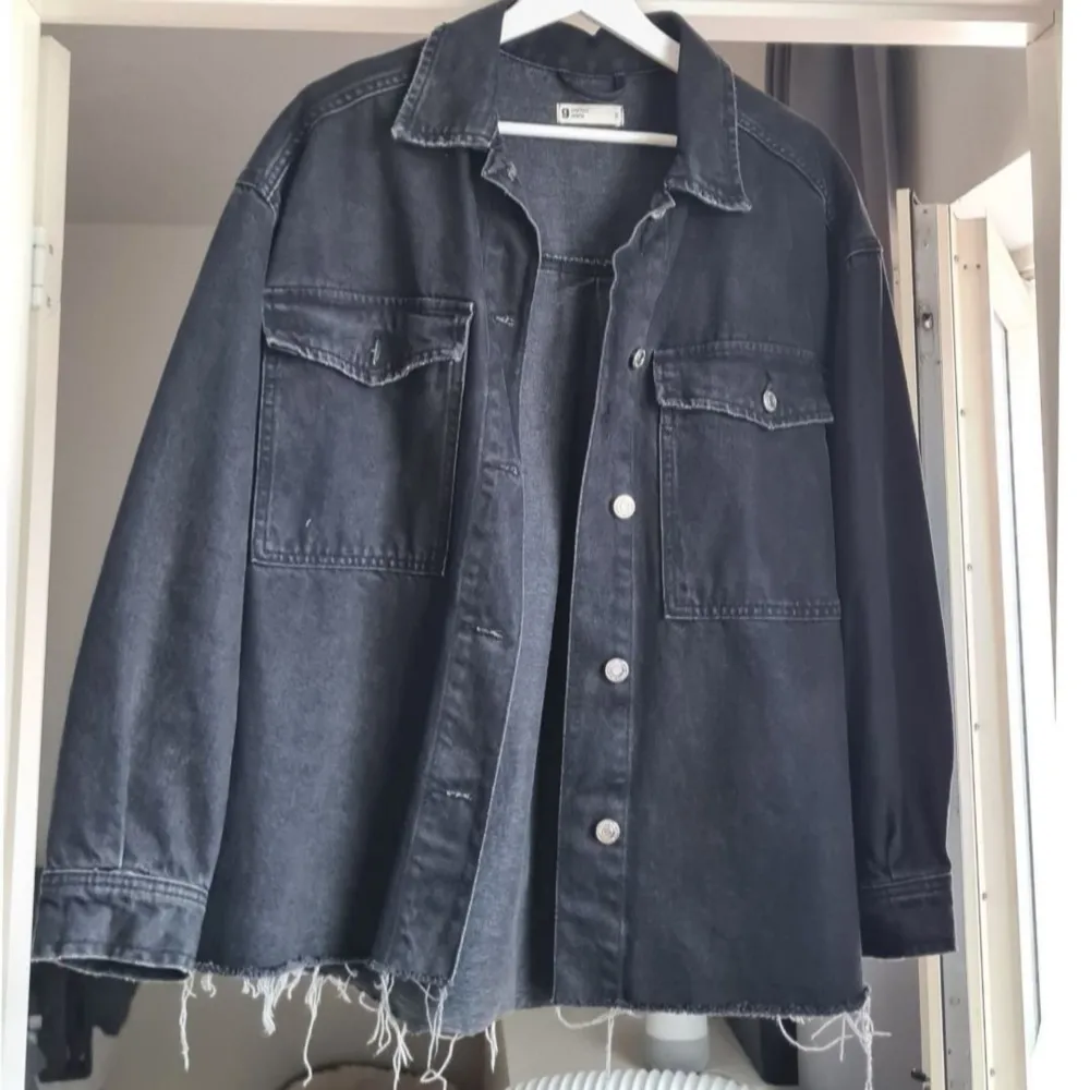 Snygg svart denimjacka med oversize passform. Från Gina Tricot. Jackan har knappstängning framtill och två fickor på bröstet. Snygg sliten look.  Storlek S. Nyskick.. Jackor.