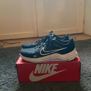 Säljer ett par svarta Nike sneakers i mycket bra skick. De har en vit sula och klassisk Nike-logga i vitt på sidan. Skorna har snörning och är perfekta för träning eller vardagsbruk. De är bekväma och stilrena, passar till det mesta! Kan även gå ner i pris vid snabb affär