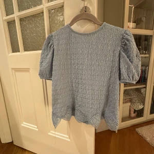 Ljusblå blus/topp från Zara - Säljer en superfin ljusblå topp från Zara. Den har korta puffärmar och ett snyggt spetsmönster längst ner. Perfekt för vår och sommar! 🦋Bra skick!