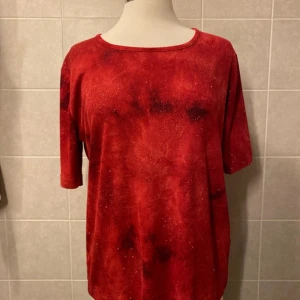 Top från XLNT by Kappahl strl 42/44 - Strl 42/44 En röd topp med glittrande detaljer. Toppen har en rund halsringning och korta ärmar. Den är tillverkad i ett mjukt och bekvämt material. 100% Polyester 