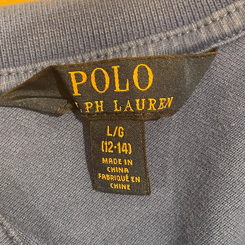 Säljer en klassisk blå pikétröja från Ralph Lauren i storlek 12-14. Tröjan har korta ärmar och en liten rosa logga på bröstet. Perfekt för en avslappnad men stilren look. Använd men i bra skick.. T-shirts.