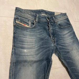 Blå jeans från Diesel - Säljer ett par snygga blå jeans från Diesel i bra skick. De har en klassisk femficksdesign med knappgylf och är i en slim passform. Perfekta för både vardag och fest! 🕺
