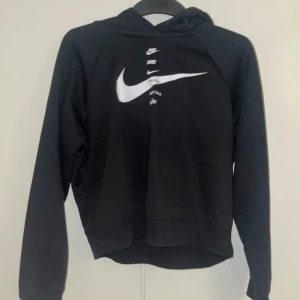 Svart hoodie från Nike - Säljer en svart hoodie från Nike i mycket bra skick. Den har en stor vit Nike-logga på framsidan och är perfekt för både vardag och träning. Hoodien har långa ärmar och en bekväm passform. Perfekt för höst och vinter!