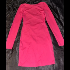 Långärmad rosa klänning  - En jätte fin skrik rosa klänning (använt Max 2 gånger) med detalj på ryggen, finns en liten defekt som jag visar på tredje bilden men går säkert att tvätta bort!! 