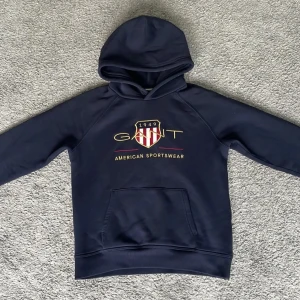 Blå Gant Hoodie - Idag säljer jag denna marinblåa hoodie från Gant i storlek 158-164, hoodien har använts runt ett dussin gånger och är i bra skick som man kan se i bilderna✅