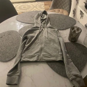 Grå hoodie från H&M Divided - Säljer en grå hoodie från H&M Divided i storlek XS. Den är supermjuk och perfekt för höst och vinter. Hoodien har dragkedja och långa ärmar med ribbade muddar. Perfekt för en avslappnad stil eller mysiga dagar hemma. 🩶