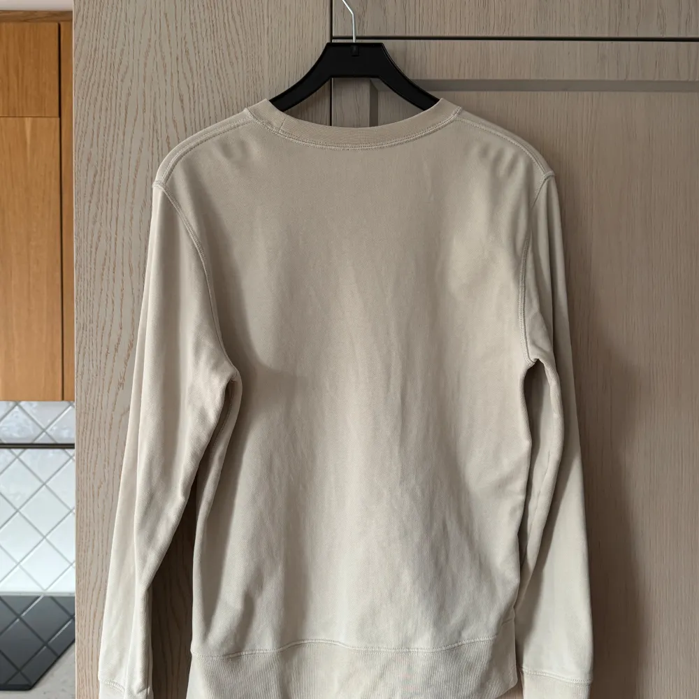 Säljer en stilren beige sweatshirt från Arket i storlek S. Den har en klassisk rund hals och långa ärmar, perfekt för en avslappnad look. Tröjan är i bra skick och passar till alla säsonger. Perfekt för både vardag och mysiga hemmakvällar!. Tröjor & Koftor.