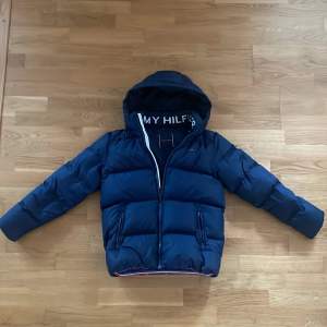 Säljer en super snygg Tommy Hilfiger vinter jacka som är super varm och skön under vintern.  Den har bara varit använd under en vinter men har fått ett litet hål på högra back ärmen som knappast syns och vissas på en av bilderna.   