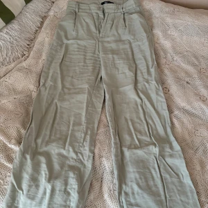 Beige byxor från Gina Tricot - Säljer ett par snygga gröna byxor från Gina Tricot. De är i storlek 36 och har en stilren design med raka ben och en hög midja passform. Perfekta för både vardag och fest!