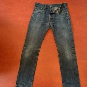 Levi's 501 jeans - Säljer ett par klassiska Levi's 501 jeans i blå denim. De har en straight passform och är i välanvänt skick. Perfekta för en avslappnad stil och funkar året runt. Jeansens ikoniska design med fem fickor och knappgylf gör dem tidlösa och alltid trendiga.