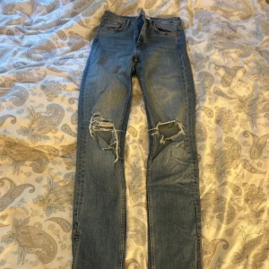 Blå jeans med slitningar - Säljer ett par snygga blå jeans med slits, lite söndriga på ena benet längst ner men inget som man tänker på.