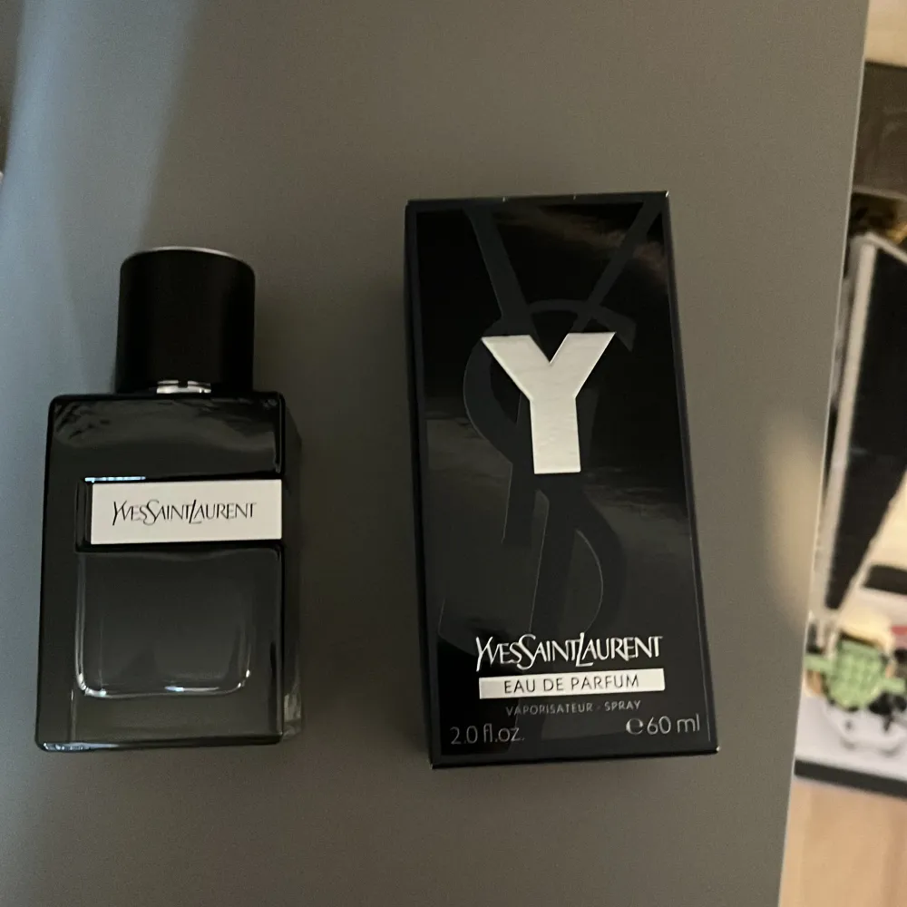 Säljer en elegant och stilren parfym från Yves Saint Laurent. Flaskan är svart och fyrkantig med en modern design. Parfymen är en Eau de Parfum och kommer i en 60 ml flaska. Perfekt för den som vill ha en sofistikerad och maskulin doft.. Parfym.