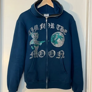 Mörkblå hoodie med glittrigt tryck - Säljer en snygg mörkblå hoodie från Aim for the Moon. Den har en dragkedja framtill och en mysig huva. Perfekt för höst och vinter!