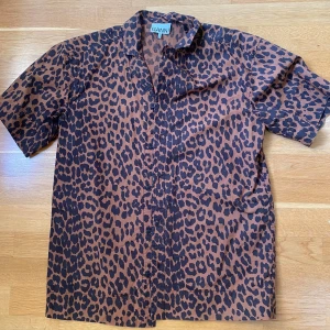 Ganni kortärmad skjorta  - Brand: GANNI  Vad: Skjorta kortärmad Strl: 32 (S-M) Material: 100% organisk bomull  Skick: Använd fåtal gånger, färg och passform näst intill som ny. Färg: Brun och svart  Pris: 699kr inklusive frakt. 