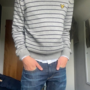 Grå randig tröja från Lyle & Scott - Säljer en grå tröja från Lyle & Scott i storlek M, passar även S. Den har ett randigt mönster i mörkare grå färg och en gul logga på bröstet. Tröjan är långärmad och perfekt för hösten! Den är i bra skick och bekväm att ha på sig. Skriv för frågor!🤙