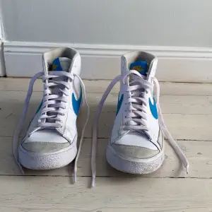 Nike modell blazer mid, mellanhöga skor vita med blå swoosh och beige bakflik med gul text storlek 36,5  nästan helt oanvända