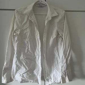 Vit långärmad skjorta från Bexleys - Säljer en vit långärmad skjorta. Skjortan är i bomull och har en klassisk krage med knappar framtill. Perfekt för både vardag och fest. Skjortan är i nyskick men behöver strykas för att få bort skrynklorna.