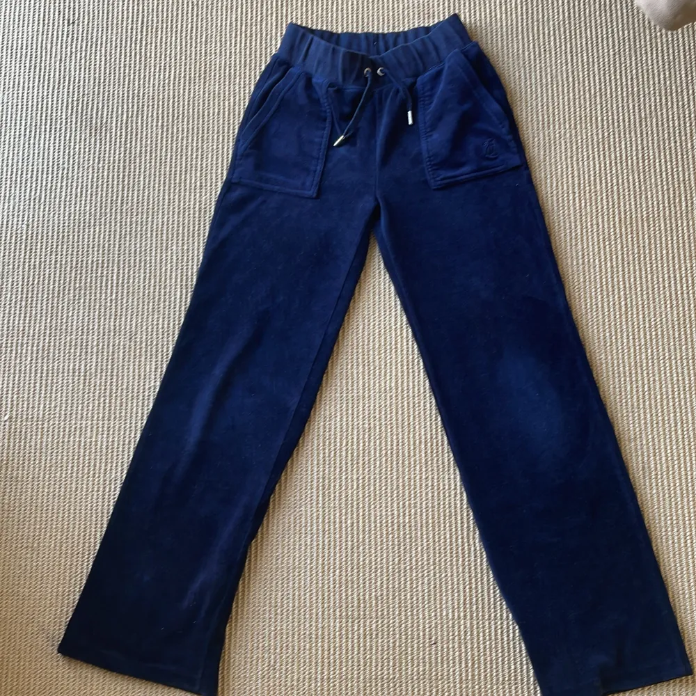 Säljer ett par mörkblå mjukisbyxor från Juicy Couture i storlek XXS. Byxorna har en låg midja med snörning och raka ben. Byxorna har också fickor fram och en bakficka med knapp.. Jeans & Byxor.