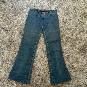 Blå jeans från Miss Sixty - Säljer ett par snygga blå jeans från Miss Sixty. De har en mid waist och en bootcut-stil som ger en retro vibe. Jeansen är i bra skick och har en dragkedja framtill. Perfekta för både vardag och fest!