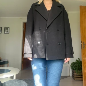 Svart kort kappa - Svart kort kappa från Nelly i storlek S i superbra skick. För referens är jag 175cm lång. Lite oversize. Använd gärna köp nu funktionen