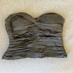 Bandeau topp - Oanvänd topp. Det är dragkedja i ryggen och passar vid brösten. Grön/grå färg.