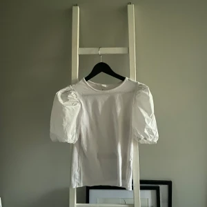 Vit kortärmad topp med puffärmar - Säljer en superfin vit topp i storlek S. Den har korta puffärmar som ger en söt och trendig look. Perfekt för både vardag och fest! Toppen är i bra skick och passar till alla tillfällen. Köp den nu och uppgradera din garderob! 💖