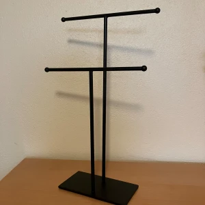 Svart smyckesställ från H&M Home - Säljer ett stilrent svart smyckesställ från H&M Home. Perfekt för att organisera och visa upp dina smycken. Stället har två nivåer och en stabil bas. Passar bra i alla rum och håller dina smycken prydligt och lättillgängligt.