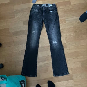 Svarta jeans från LTB - Säljer ett par svarta jeans från LTB i modellen Valerie. De är i storlek 24/30 och har en snygg slitning på låren. Jeansen är i bootcut-stil och har en låg midja. Perfekta för en cool och avslappnad look! helt nya