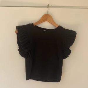 Svart volangtopp - Svart volangtopp från ZARA. Lite nopprig men inte mycket. Annars är den i bra skick.