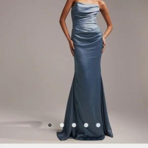 Maxiklänning i satin och bandeu modell - Långklänning i dimblå färg. Ej använd då den kom efter min bal. Den är i storlek M, men är liten i storleken. Kostade från början 1569kr.