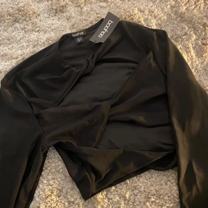 Svart top - Svart snygg top med detaljer framtill helt oanvänd 
