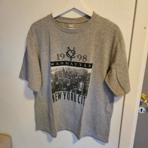 Grå t-shirt med New York City-tryck från 157 - Säljer en grå t-shirt från lager157 med tryck framtill. T-shirten är i storlek M. väldigt mjuk och bra skick