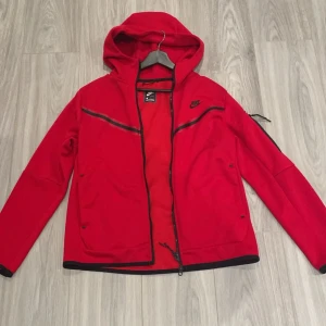 Röd jacka från Nike - Säljer en snygg röd jacka från Nike i storlek M. Den är bara använd 4-5 gånger. Perfekt för höst och vår, med en sportig look som passar både till träning och vardag. Den är i bra skick och redo för nya äventyr! Säljer pga de är inte min stil.Helt ny