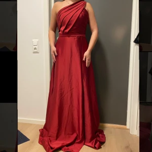 Mörkröd balklänning - Vinröd/mörkröd balklänning från LaDonatella. Avtagbar blomma (se bild 3). Storlek 38 men passar snarare storlek 36.