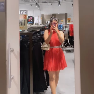 Röd kortklänning med silverdetaljer - Säljer en superfin röd kortklänning som är perfekt för fest! Den har en snygg silverdetalj i midjan som ger en extra touch. Klänningen är ärmlös och har en luftig passform, vilket gör den bekväm att bära hela kvällen. Perfekt för sommarens alla fester! 💃