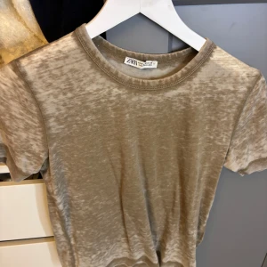 Beige t-shirt från Zara - Säljer en snygg beige t-shirt från Zara. Den är kortärmad och har en normal passform. Perfekt för en avslappnad stil och kan matchas med nästan vad som helst. T-shirten är i bra skick och redo för en ny ägare!