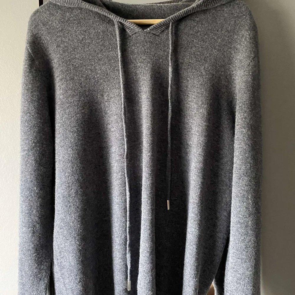 Säljer en supermysig grå stickad cashmere hoodie som är perfekt för kyliga dagar. Den har en avslappnad passform med långa ärmar och en klassisk huva med snören. Perfekt för både höst och vinter!. Tröjor & Koftor.