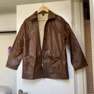 Läderjacka - Snygg läderjacka i brun PU! Tunn och passar perfekt till sen vår/tidig höst och sommarkvällar!🤩 Våkdigt fint skick men behöver komma till användning för att räta ut sig! Storlek XS men passar även S!