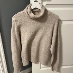 Beige stickad tröja med krage - Stickad tröja från H&M med krage. Tröjan är använd fåtal gånger och är något nopprig men inget som syns värst mycket. Skriv vid frågor eller intresse!