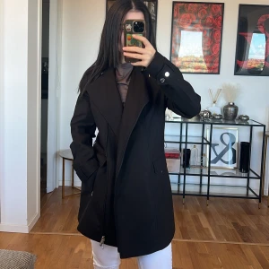 Svart kappa med dragkedja Calvin Klein 💞 - Säljer en stilren svart kappa med dragkedja och knappar på ärmarna. Den har en klassisk design med långa ärmar och en snygg krage. Perfekt för höst och vår, och funkar lika bra till vardags som till fest. Passformen är normal och materialet känns sli