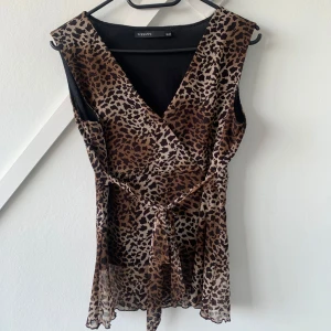 linne i leopard - v-ringat linne i leopardmönster. går att knyta både i sidan och ryggen beroende på vilken look man vill åt. leopardtyget är i mesh med bubblig fåll. 