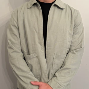 Jacka med dragkedja - Säljer en stilren ljusgrön jacka med dragkedja framtill. Jackan har en klassisk krage och två stora fickor på framsidan. Perfekt för vår och höst! Passar bra till både vardag och lite mer uppklädda tillfällen.