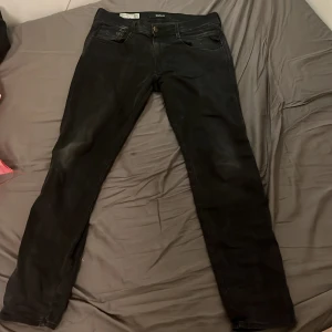 Svarta Replay anbass hyperflex - Svarta replay Jeans med ljusnande ”slitningar” i den populära modellen anbass. Dessa jeans är hyperflex så de är väldigt sköna och tack vare elasticiteten spänns de åt vid midjan och passar utmärkt till folk med olika storlekar